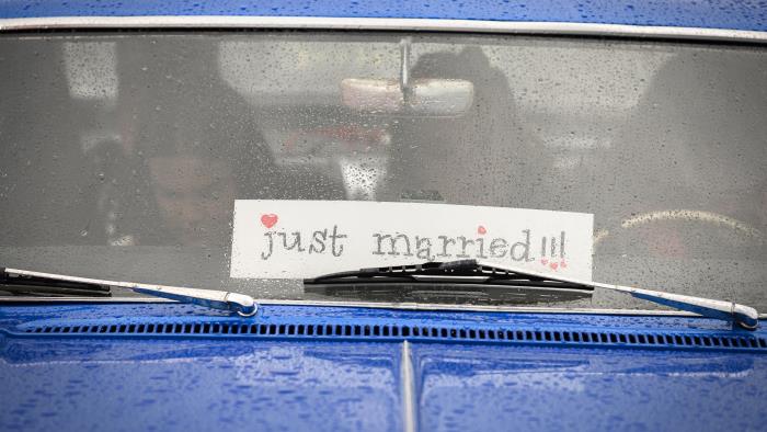 En blå bil med en skylt med texten Just married i framrutan.
