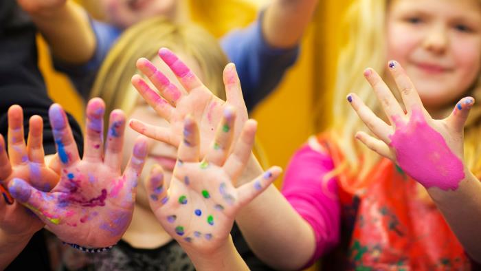 Glada barn med målarfärg på händerna.