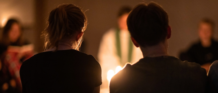 Två personer sitter i en ring med några andra ryggen mot kameran.