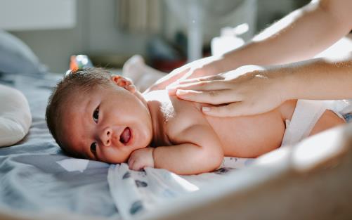 En baby på mage får massage på ryggen. 