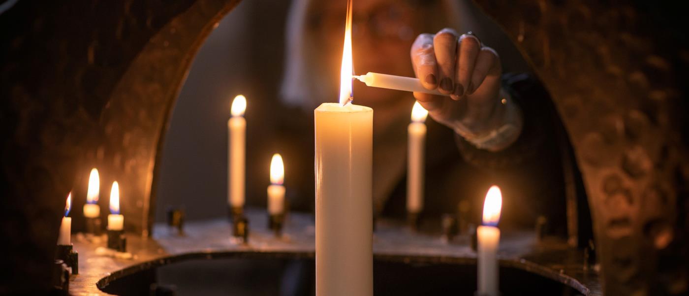 Kvinna tänder ljus i kyrka. 