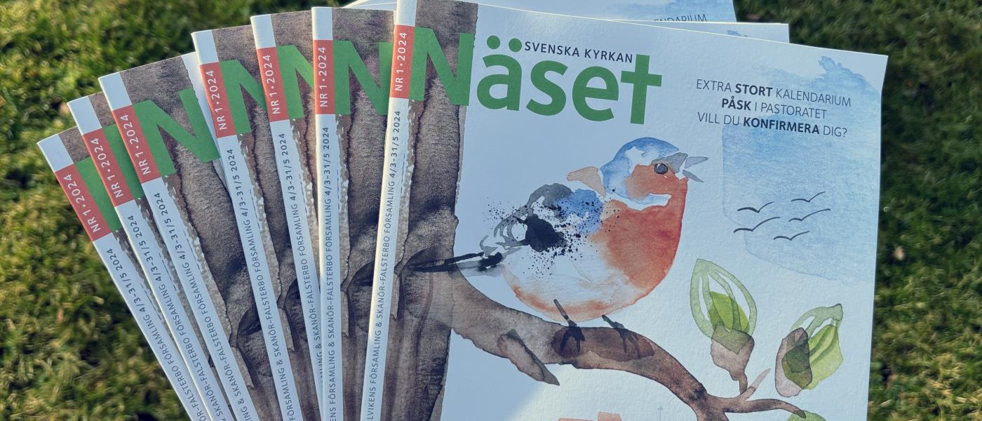 Person visar upp flera nummer av tidningen Näset från Näsets pastorat