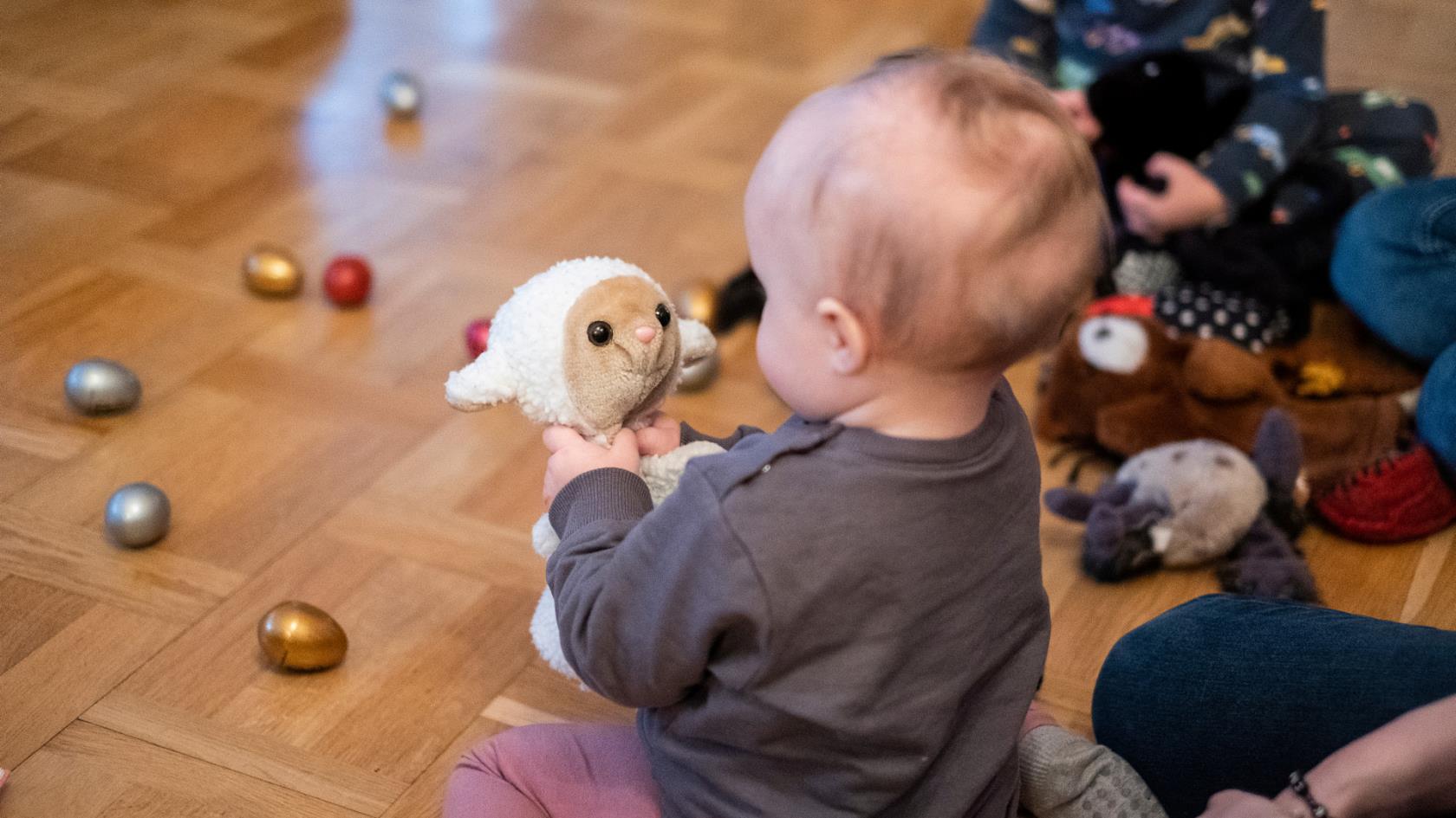 Bebis leker med ett gosedjur på golvet