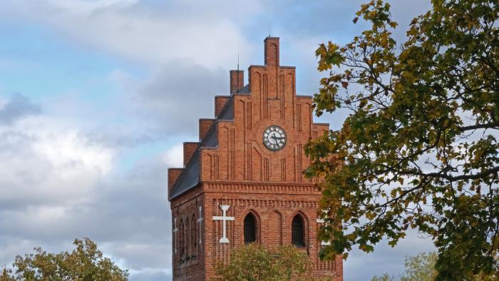 Torshälla kyrktorn. Grenar med höstlöv.