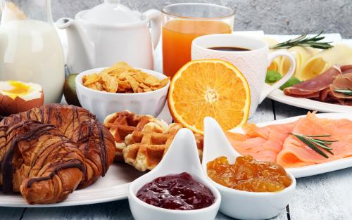 Uppdukat frukostbord med bröd, kaffekanna, marmelad mm