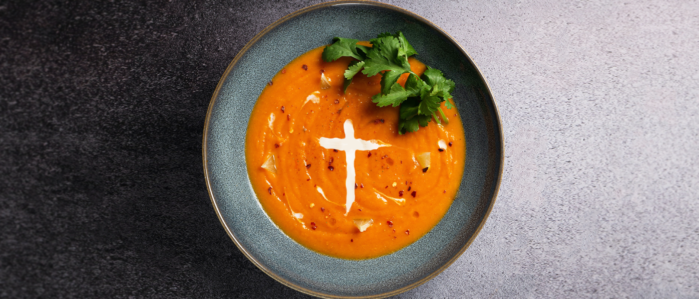 En tallrik med soppa. Gräddfilen i soppan är i formen av ett kors.