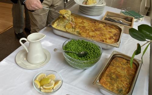 En person tar mat från ett buffébord med ärtor och annat.