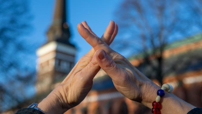 Bild på händer som tecknar ordet kyrka. 