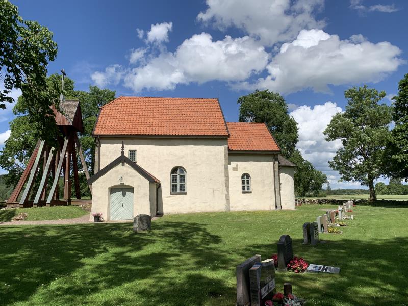 Östra Gerums kyrka med kyrkogården runt omkring samt grönskande träd och grönt gräs.