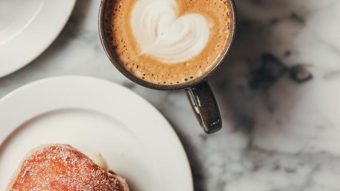 Kaffe med ett hjärta i mitten och en bulle.