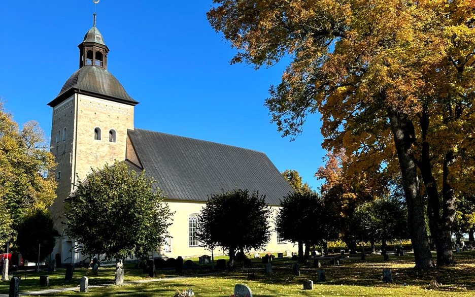 Vit kyrka med höstträd bredvid