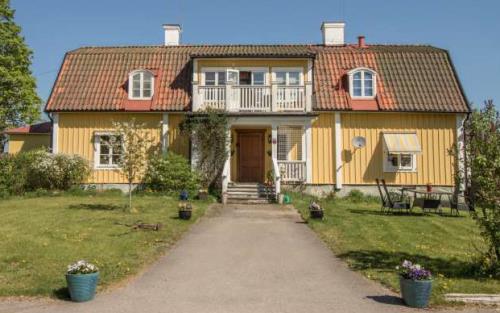 Stor villa med gul träpanel, rött tegeltak, veranda och balkong