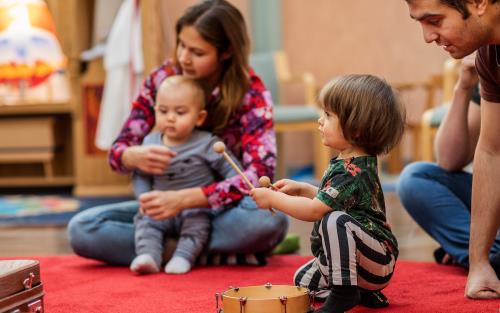 Barnfamilj leker och spelar musik i en kyrka