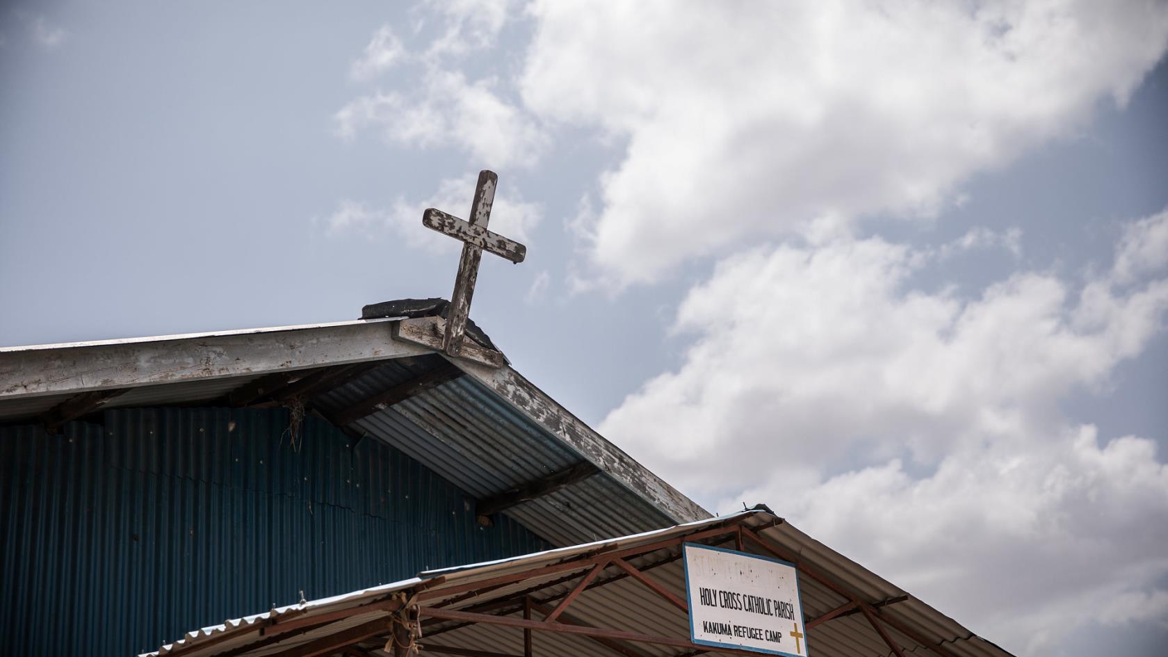 Ett kors på kyrktak mot blå himmel 