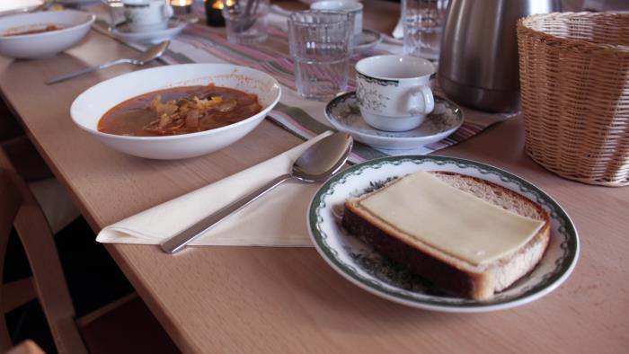 Tallrik med soppa och assiett med brödskiva med ostsmörgås