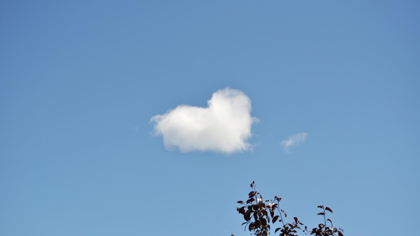 Ett moln har formen av ett hjärta på den blå himlen.