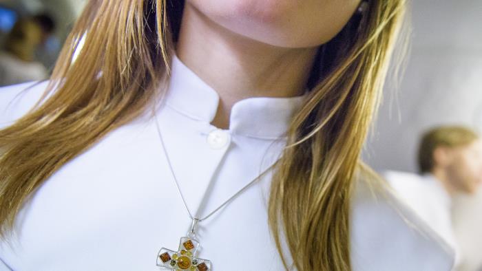 En konfirmand har ett halsband med ett kors runt halsen.