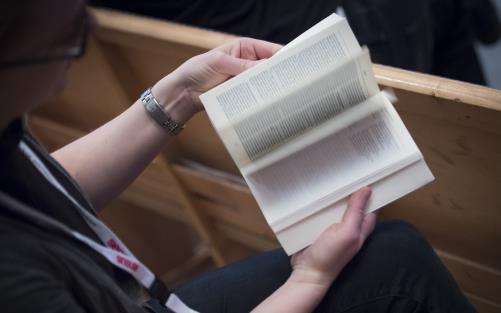 En person sitter och bläddrar i en bibel.