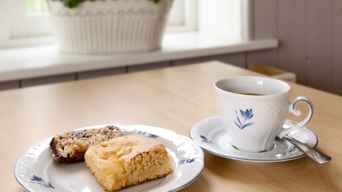 En kopp kaffe och ett fat med fikabröd står på ett bord.