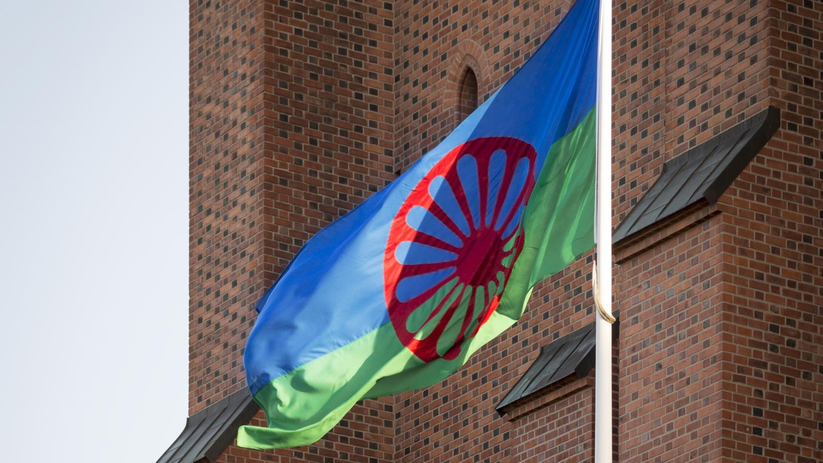 En flaggstång med den romska flaggan hissad står utanför Uppsala domkyrka.