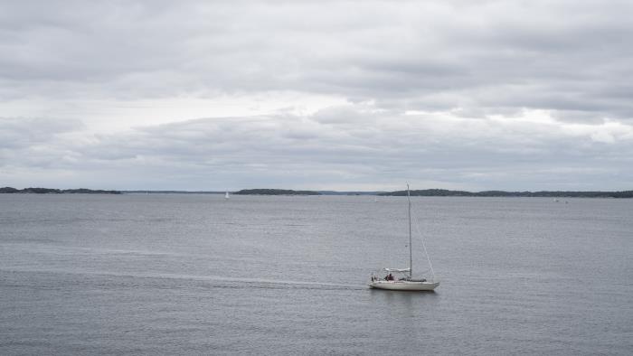 En segelbåt går för motor en molnig dag.