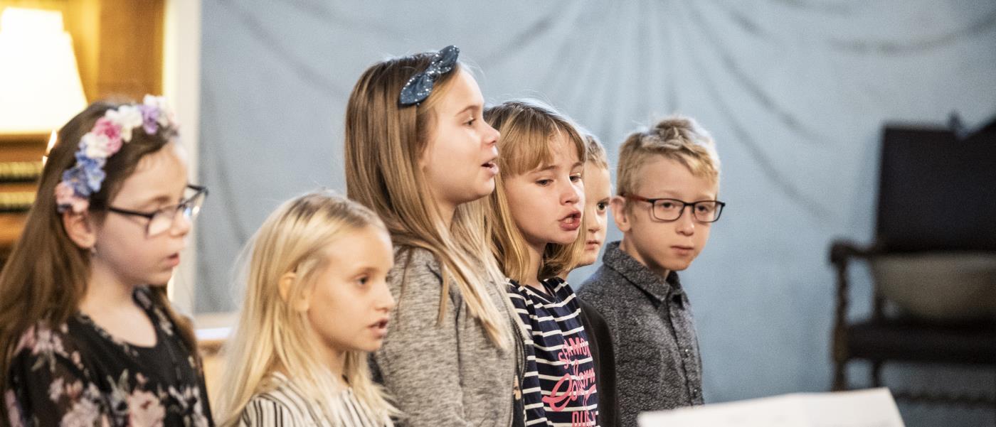 Några barn står bredvid varandra och sjunger framme i kyrkan.