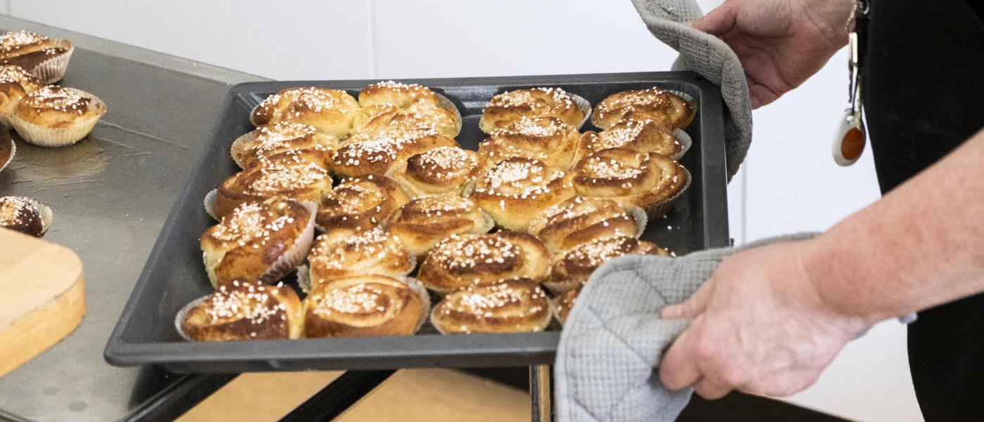 Någon ställer ifrån sig en plåt nybakta kanelbullar.