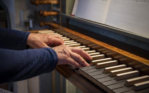 Ett par händer spelar på en kyrkorgel.