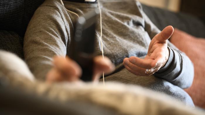 En präst sitter med hörlurar och pratar i mobiltelefon.