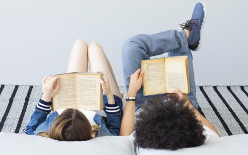 Två ungdomar ligger i en soffa och läser varsin bok.