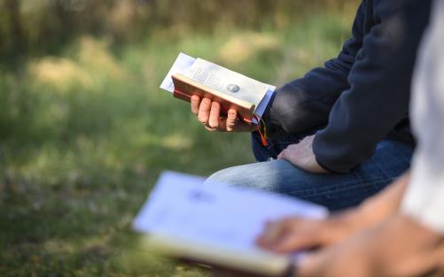 Två personer sitter bredvid varandra utomhus med varsin psalmbok.