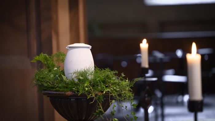 En urna står uppställd bland ormbunksblad i kyrkan.