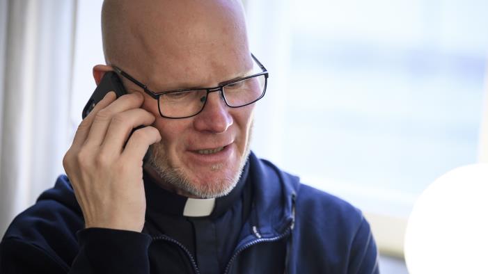 En manlig präst pratar i mobiltelefon.