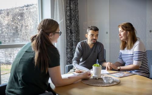 En kvinnlig diakon sitter och samtalar med en man och en kvinna som håller hand.