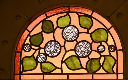 Ett kyrkfönster med en glasmålning som föreställer gröna blad.