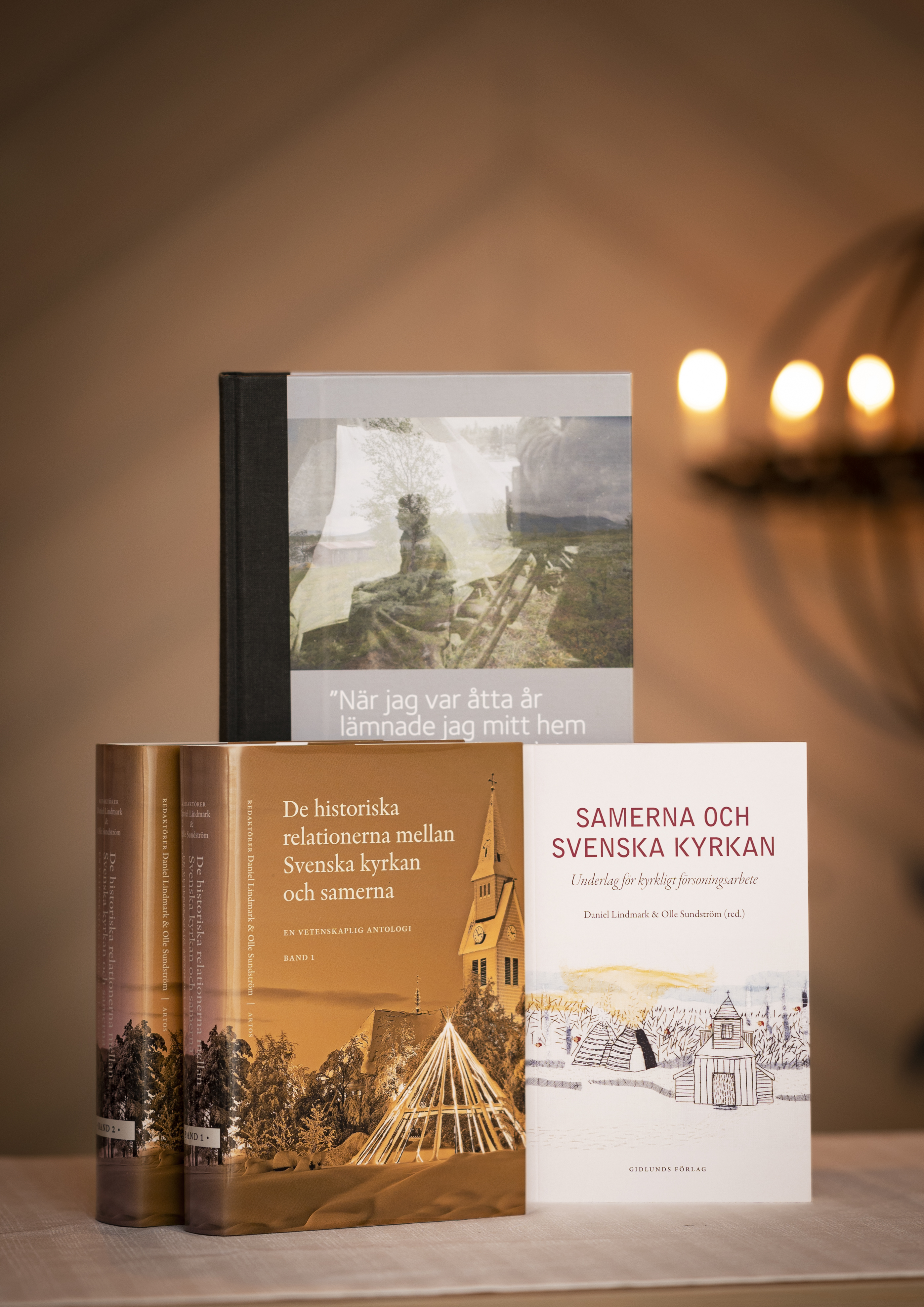 Tre böcker om Svenska kyrkan och samerna står uppställda på ett bord.