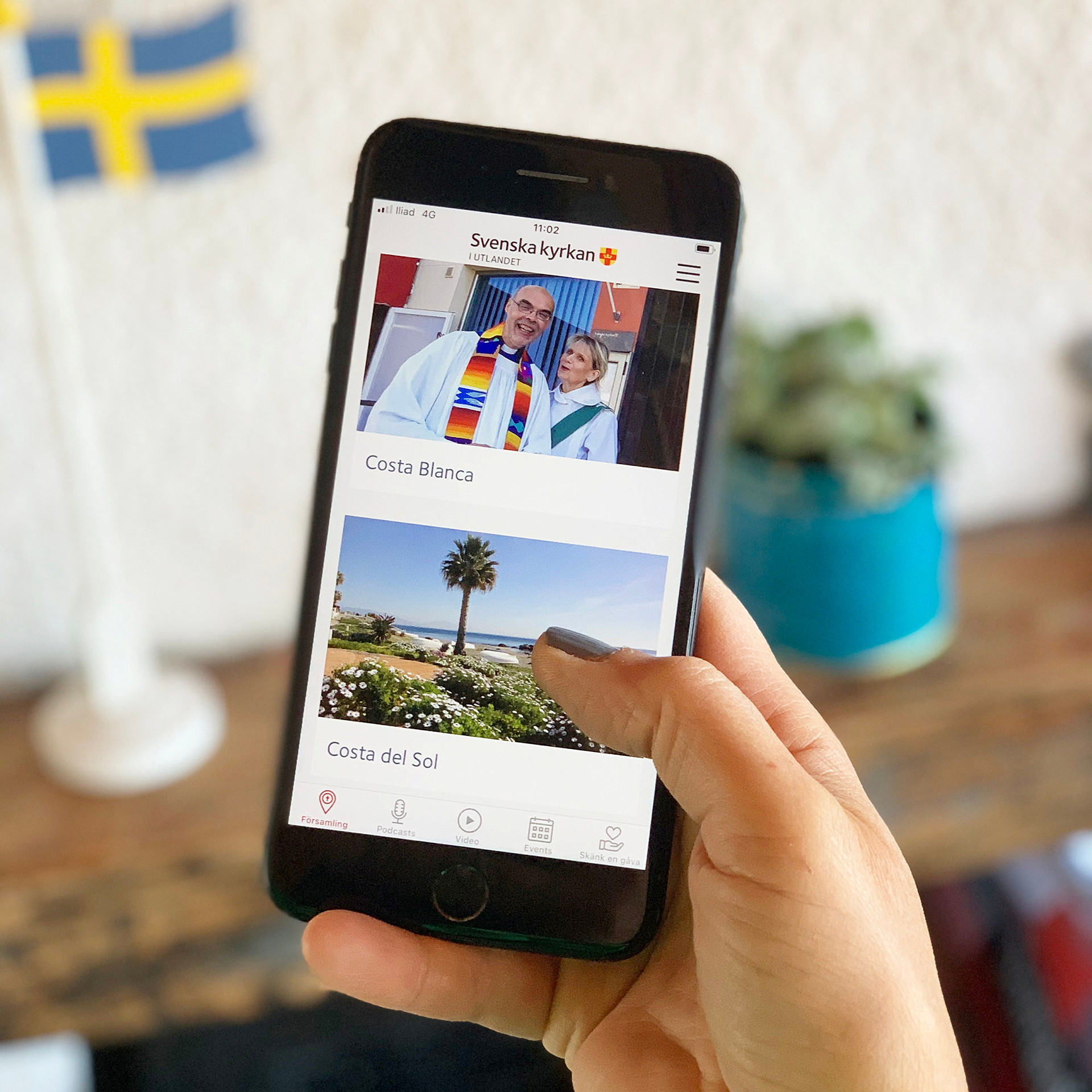 En kvinna håller en mobiltelefon i handen och på bilder präst och diakon.