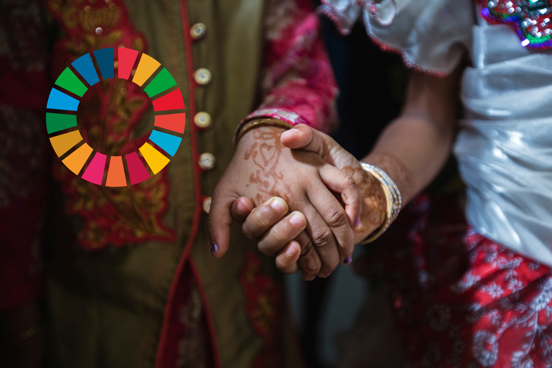 Två personer med hennatatueringar håller varandra i handen. Till vänster syns loggan för Agenda 2030.