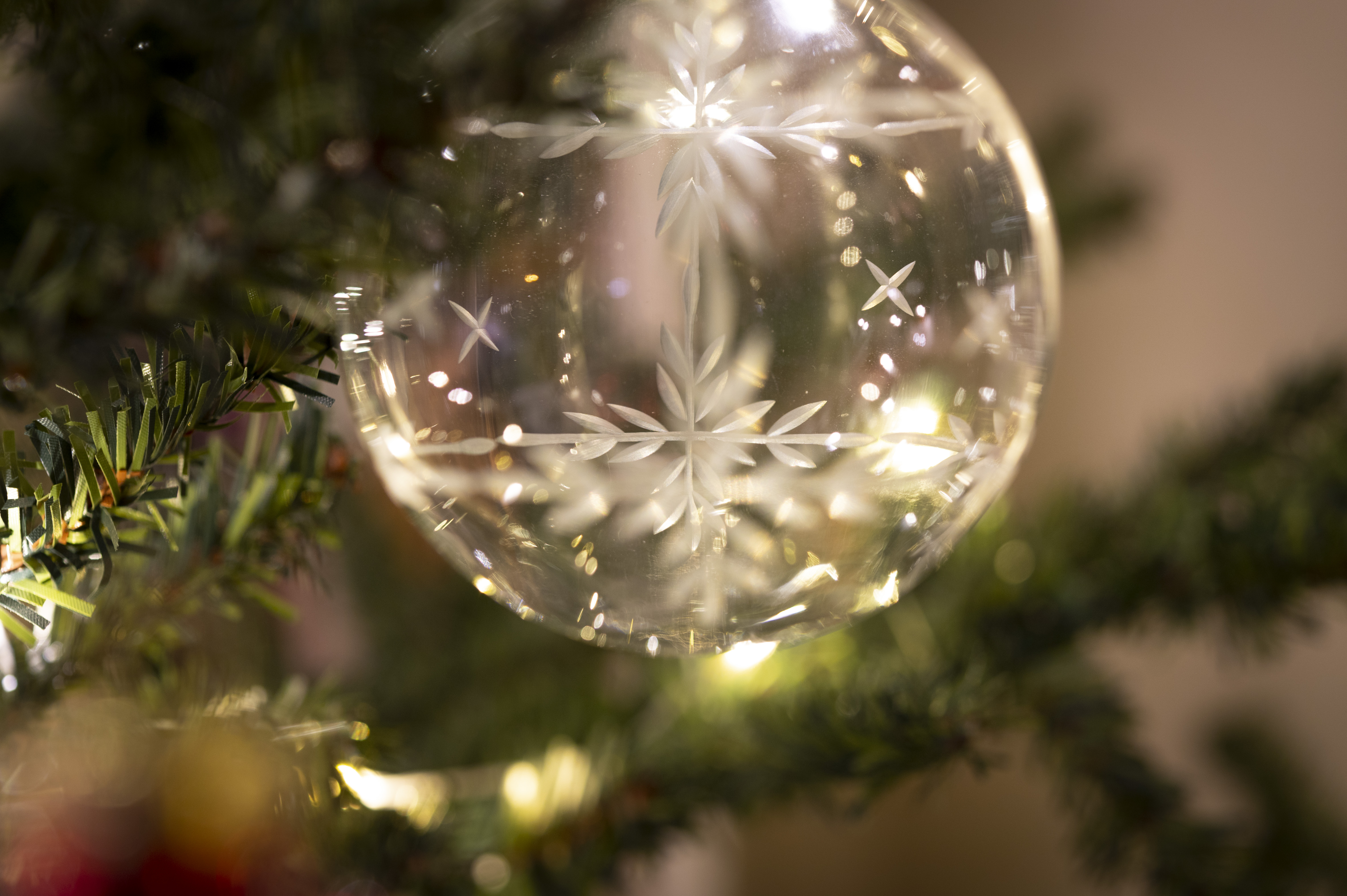 Närbild på en ljusgul genomskinlig julgranskula i en gran. B