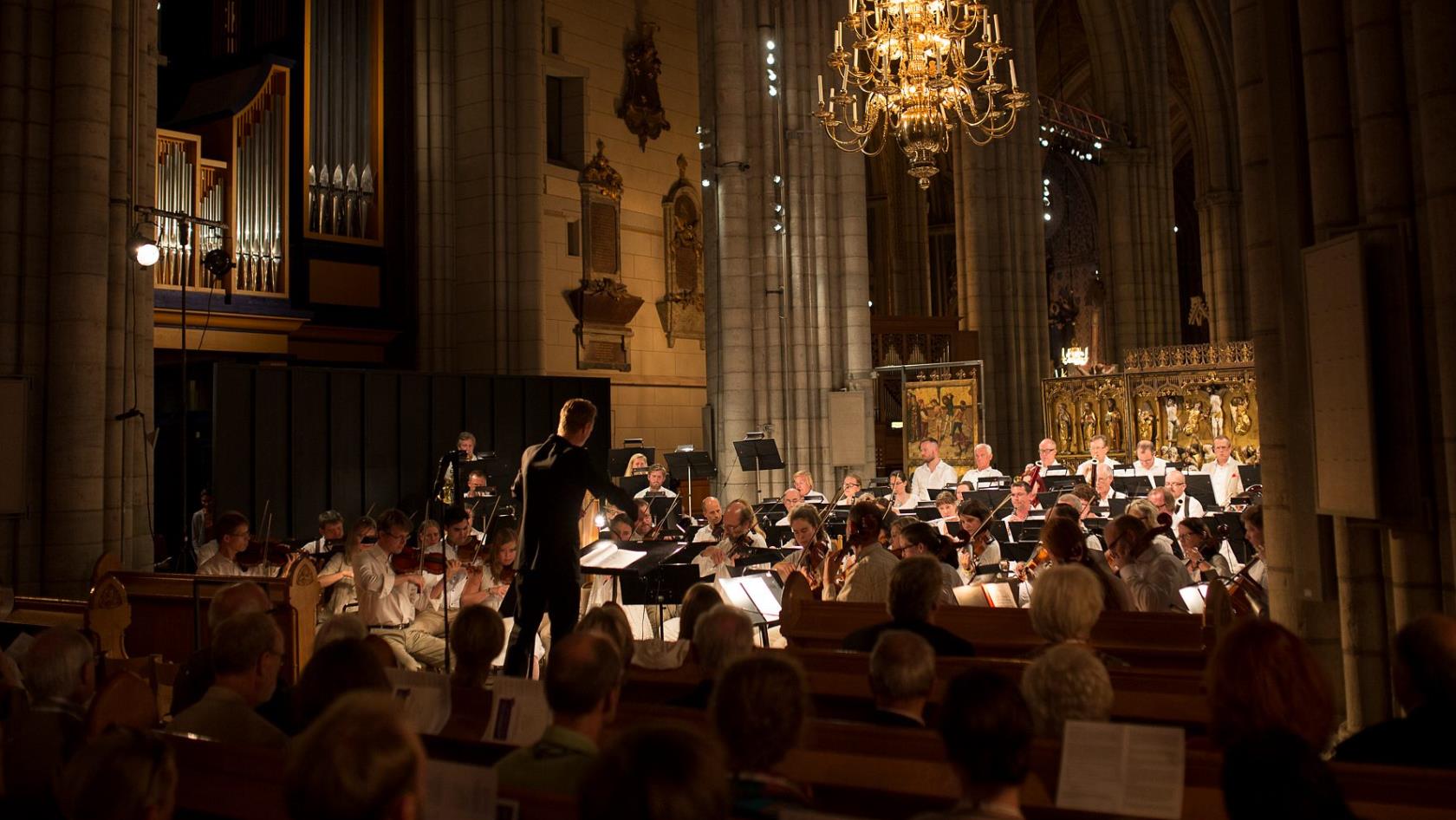 Orkester med dirigent spelar i kyrka.
