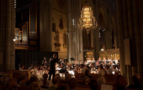 Orkester med dirigent spelar i kyrka.