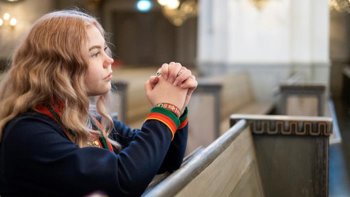 Flicka ber i kyrka och bär traditionella samekläder