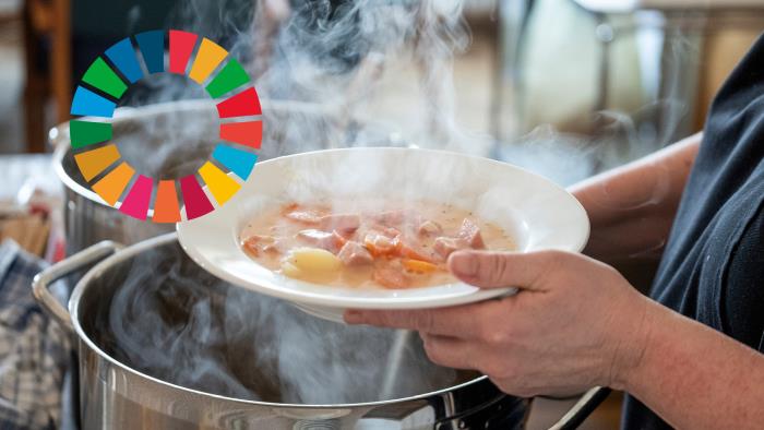 Någon tar soppa ur en stor kastrull. Till vänster i bilden syns loggan för Agenda 2030.