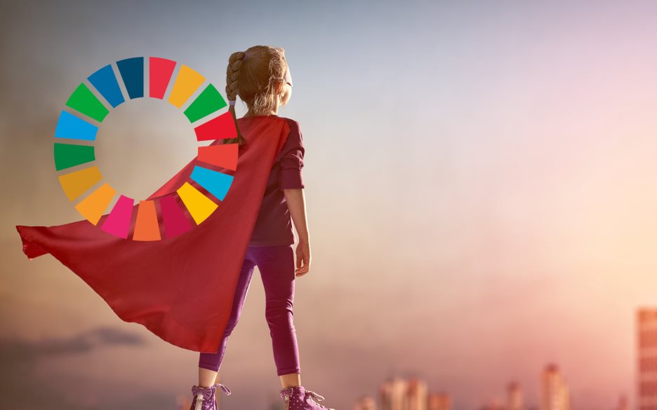 En liten flicka i lila kläder, mask och röd mantel står på kanten av ett hustak och blickar ut över en stad. Till vänster syns loggan för Agenda 2030.