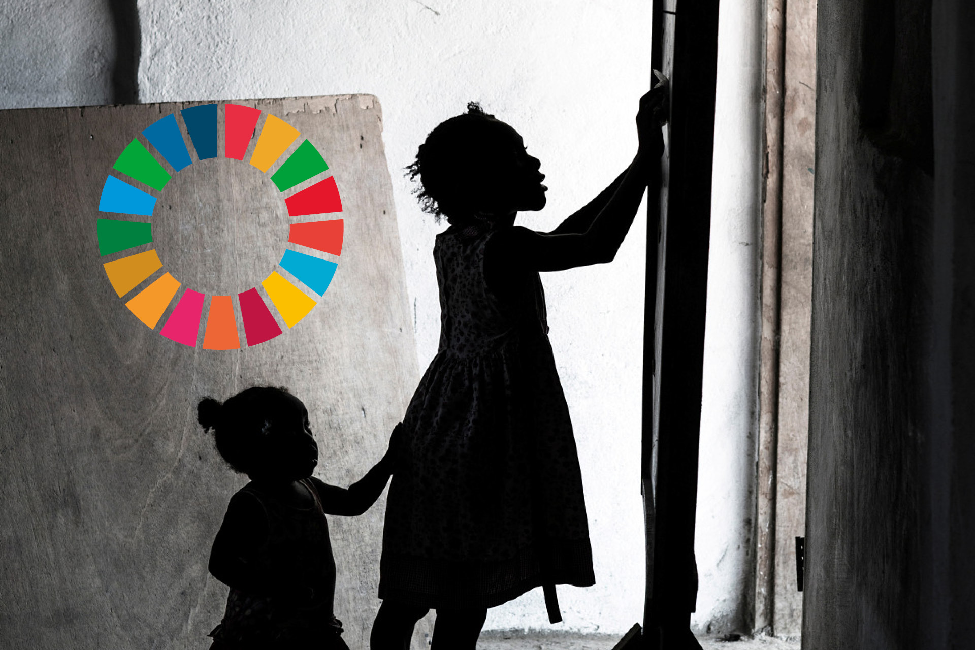 Två barn står framför en griffeltavla och skriver på den. Till vänster syns loggan för Agenda 2030.