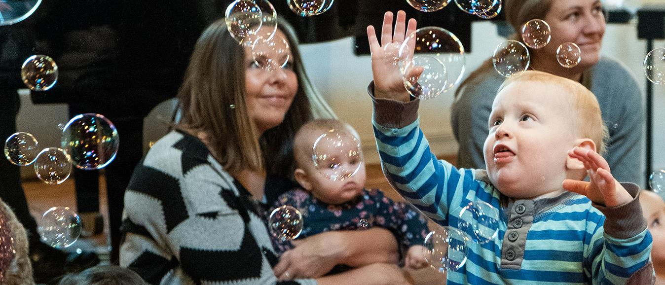 Bebis leker med bubblor på aktivitet i kyrkan för föräldrar och barn.