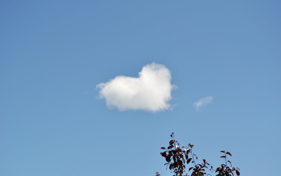 Ett moln har formen av ett hjärta på den blå himlen.