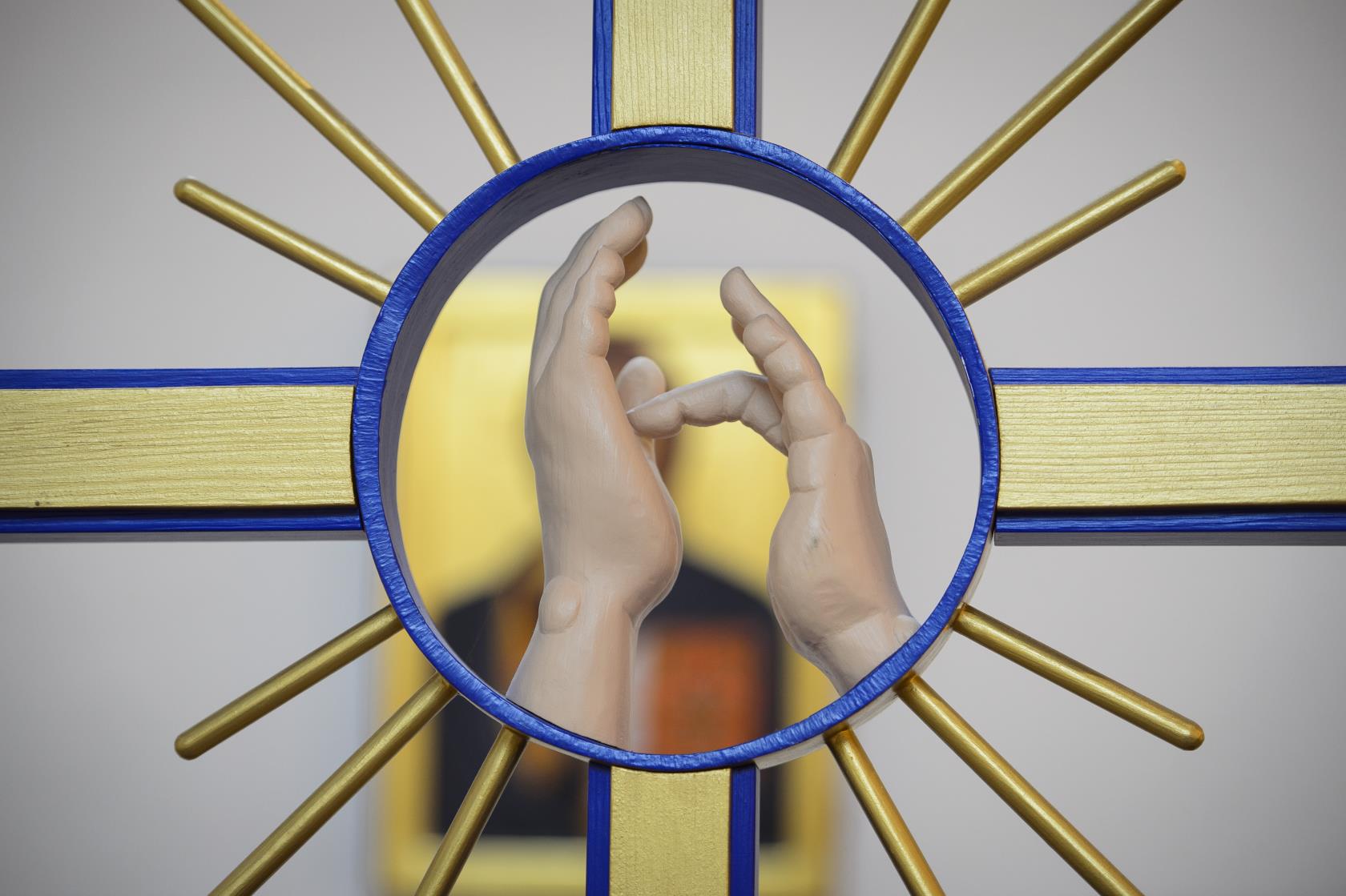 Närbild på ett altarkors med två händer som talar teckenspråk.