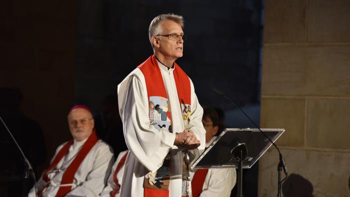 Prästen Martin Junge i strålkastarljus läser högt i Lunds domkyrka.