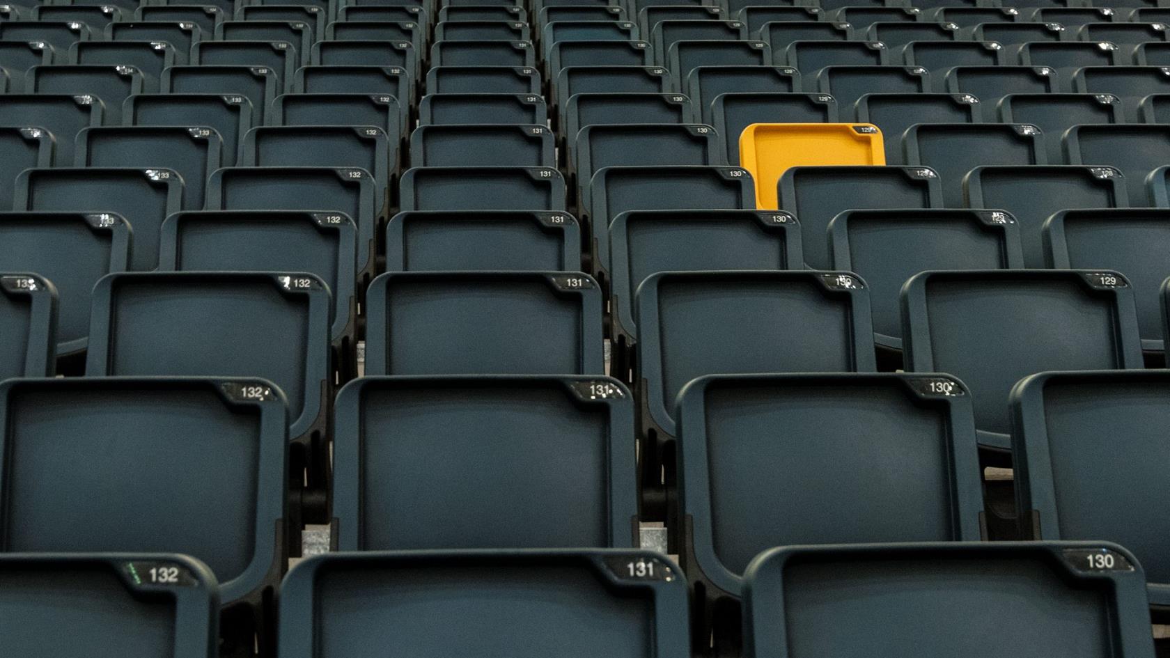 Bild av läktare på Friends Arena. En mängd svarta stolar och en ensam gul